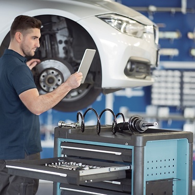 Un mecánico revisa un vehículo en un taller mientras mira una tableta