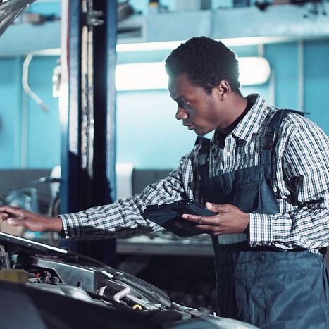 male mechanic working on passenger car with diagnostic tool