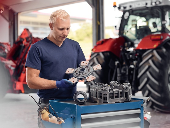 man in workshop with tractor in background